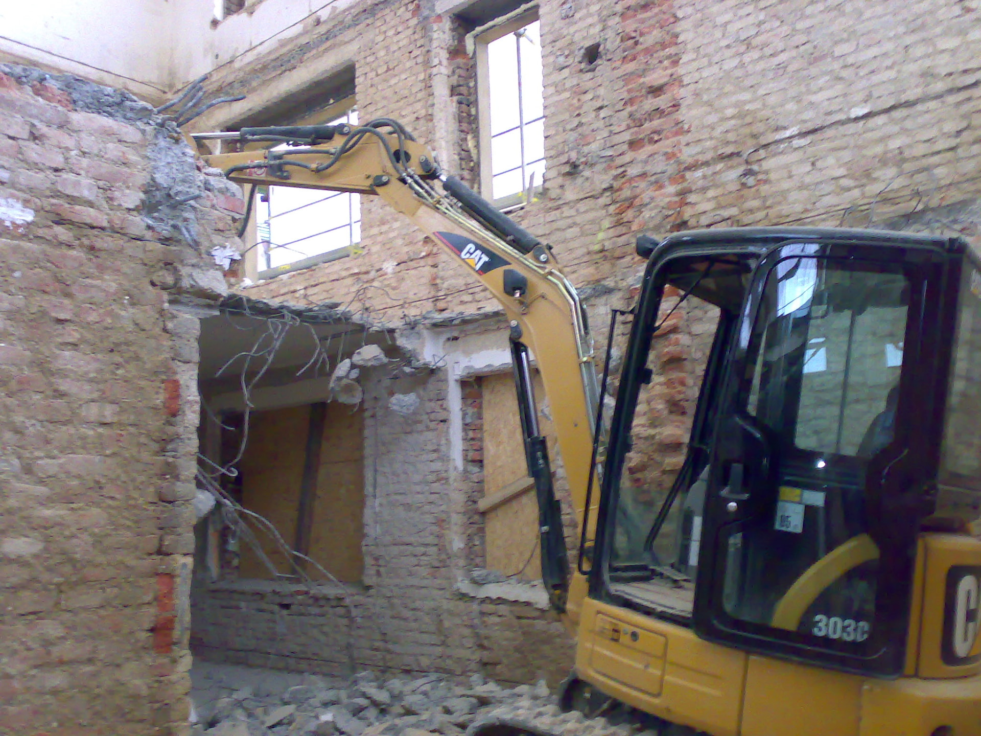 Minibagr CAT při demolici uvnitř budovy