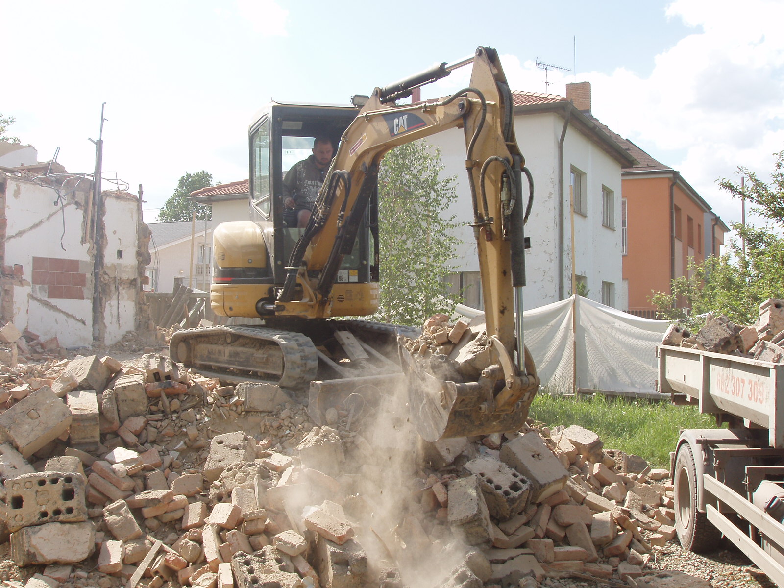 Minibagr CAT při demolici domu